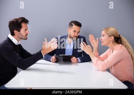 Unglücklich verheiratete Paar erhalten Geschiedene Streiten und Kämpfen Vor männlichen Rechtsanwalt im Büro Stockfoto
