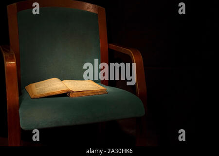 Alten Stuhl und offenes Buch in einem dunklen Stockfoto