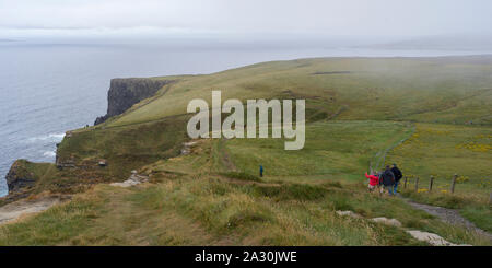 Touristen auf einer Klippe, Cliffs of Moher, Lahinch, County Clare, Irland Stockfoto