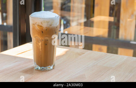 Eiskaffee im Glas auf dem hölzernen Tisch Hintergrund Glasfenster. Stockfoto