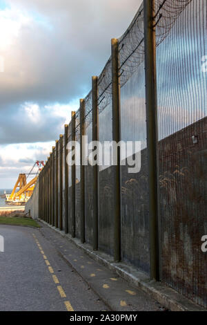 Gefängnismauern und einen Zaun mit Spikes auf dem Hintergrund des blauen Himmels. Peterhead Gefängnis Museum, Aberdeenshire, Schottland, Vereinigtes Königreich. Stockfoto