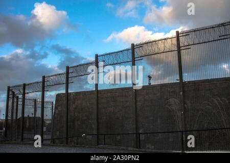 Gefängnismauern und einen Zaun mit Spikes auf dem Hintergrund des blauen Himmels. Peterhead Gefängnis Museum, Aberdeenshire, Schottland, Vereinigtes Königreich. Stockfoto