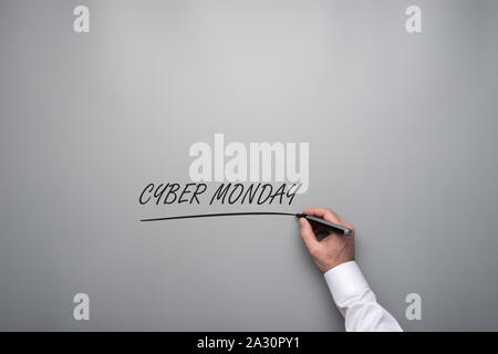 Männliche Hand schreiben eine Cyber Monday Schild über einem grauen Hintergrund mit schwarzem Marker. Stockfoto