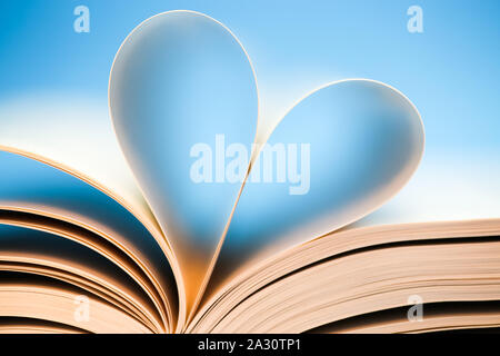 Buchen Sie Seiten auf blauem Hintergrund, glühende Herzen von Buches bilden, Stockfoto
