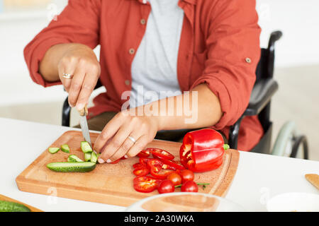 In der Nähe von Frau am Tisch sitzen und Schneiden von Gemüse auf schneidebrett sie Gemüse Salat vorbereiten Stockfoto