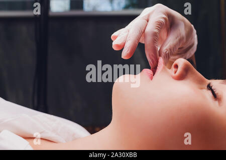 Kosmetiker macht eine bukkale Massage des Gesichts Die Muskeln des Patienten. Stockfoto