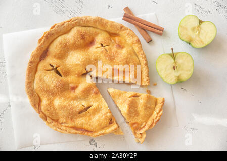 Apfelkuchen auf dem Pergament mit frischen Äpfeln und Zimtstangen Stockfoto