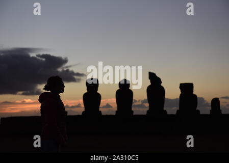 Die Osterinsel, Chile. 21 Sep, 2019. Silhouette einer Frau, die neben Moais am Ahu Tahai zeremoniellen Plattform während des Sonnenuntergangs. Moais sind monolithische menschliche Figuren, welche die Vorfahren vertreten. Sie wurden durch die Rapa Nui Menschen bei Rano Raraku, der moai Steinbruch auf der Osterinsel im östlichen Französisch-polynesien zwischen den Jahren 1250 und 1500 zeitgleich mit der Ankunft der Polynesier auf der Insel geschnitzt. Die meisten von ihnen wurden von dort transportiert und auf Stein Plattformen genannt Ahu um den Umfang der Insel. Quelle: John milner/SOPA Images/ZUMA Draht/Alamy leben Nachrichten Stockfoto