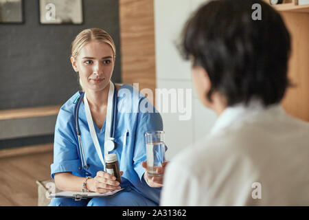 Schöne lächelnde Frau der Arzt in einer Flasche Pille bietet den Patienten. Stockfoto