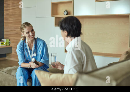 Schöne lächelnde Frau der Arzt in einer Flasche Pille bietet den Patienten. Stockfoto