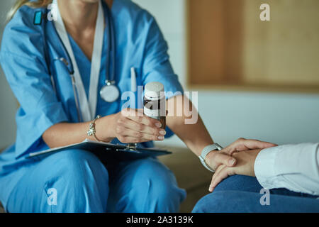 Schöne lächelnde Frau der Arzt in einer Flasche Pille bietet den Patienten. Stockfoto