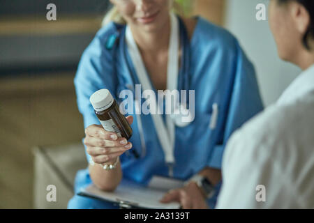 Schöne lächelnde Frau der Arzt in einer Flasche Pille bietet den Patienten. Stockfoto