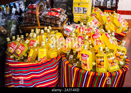 Porto da Cruz, Madeira, Portugal - Sep 24 2019: Korb mit kleinen Flaschen Poncha, traditionellen alkoholischen Getränk von Madeira. Typisch portugiesische alkoholische und nicht alkoholische Getränke. Zuckerrohr Alkohol mit Zitronensaft. Stockfoto