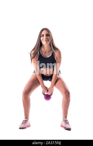 Niedrige crouching Position der jungen athletischen glückliche Frau tun kettlebell Schwingen. Voller Körper auf weißem Hintergrund. Stockfoto