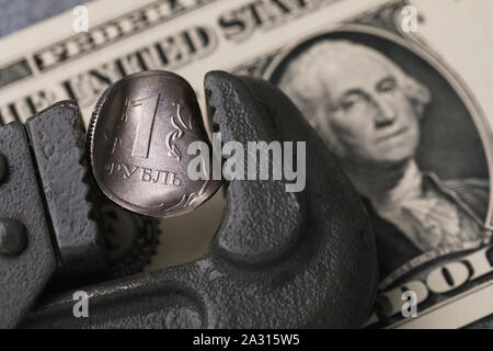 Konzept zum Thema der Fall des Rubels gegenüber dem US-Dollar. Auf der Münze gibt es eine Inschrift in russischen Buchstaben 1 Rubel ist. Münze zerquetscht von einem Stockfoto