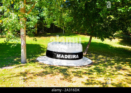 Santana, Madeira, Portugal - Sep 24, 2019: Big Strohhut im Green Park. Weißes Schild Madeira auf schwarzem Feld auf einem hutband. Traditionelle Strohhut von Madeira. Typisches Souvenir aus der portugiesischen Insel. Stockfoto