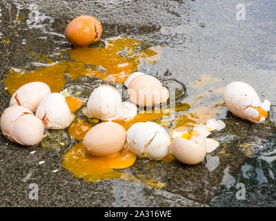 Gebrochene Eier auf nassem Asphalt, schlechten Tag bei Regenwetter. Schließen Sie herauf Bild. Schlechter Tag Konzept Stockfoto