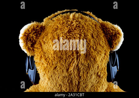 Teddy Bear mit großen Kopfhörer von hinten auf schwarzem Hintergrund Stockfoto