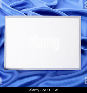 Leere Grußkarte oder Einladung mit blauem Satin Hintergrund. Stockfoto
