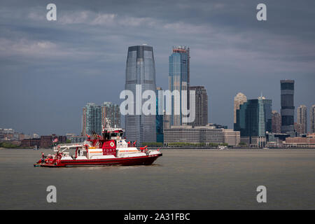 Ein New York City Feuerwehr Boot patrouilliert den Hafen in der Nähe der Freiheitsstatue. Stockfoto