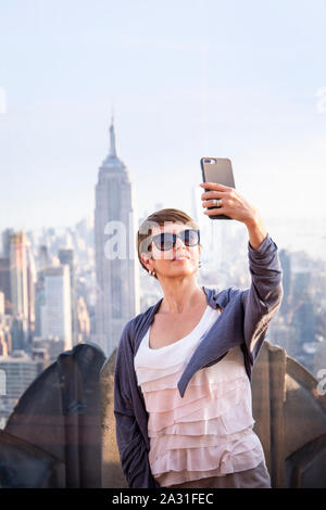 Weibliche Touristen nimmt eine selfie auf der Oberseite des Rock Observatorium mit dem Empire State Building, New York City, USA. Stockfoto