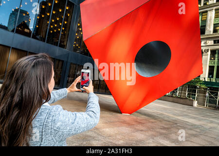 Junge Frau touristische Fotografien Isamu Noguchi's Iconic Red Cube in Lower Manhattan, New York City, USA. Stockfoto