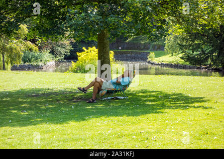 Mann sitzt in einem Liegestuhl schlafend am heißesten Tag des Jahres 2019 in der Pavilion Gardens im Peak District der Stadt von Buxton Stockfoto