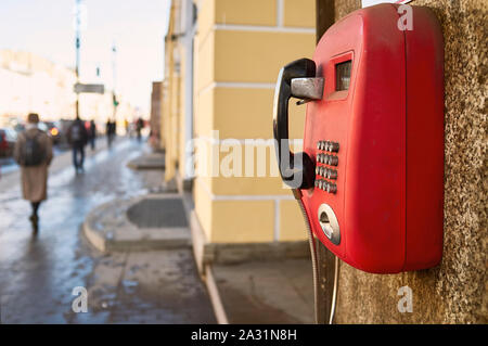 Rote Zahlen Telefon hängen an den Granit an der Wand des alten Hauses, auf dem Hintergrund von Menschen zu Fuß entlang der Straße der Stadt, sonnigen Frühlingstag. Schließen - Stockfoto