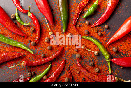 Viele rote und grüne Paprika und Pfeffer. Streuen Sie Paprika auf einem schwarzen Hintergrund, Ansicht von oben. Stockfoto