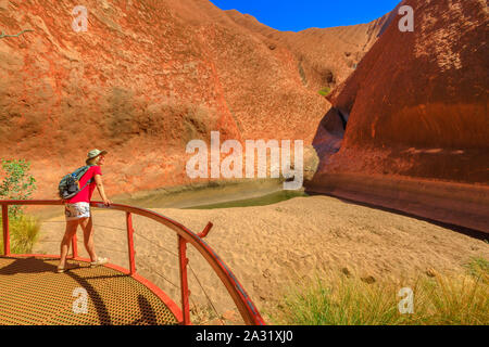 Touristische Frau am Balkon Mutitjulu Wasserloch am Ende des kurzen Kuniya Spaziergang im Uluru-Kata Tjuta National Park. Tourismus in Northern Territory Stockfoto