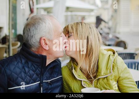 Portrait von Happy romantisches Paar mit Altersunterschied küssen draußen in der alten Stadt im frühen Frühjahr oder Herbst Stockfoto