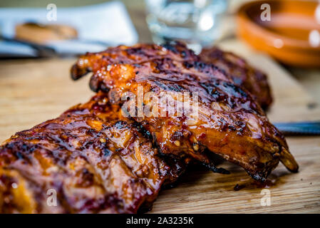 Nahaufnahme der goldfarbenen saftig gebratene Spareribs auf einer Holzplatte Stockfoto