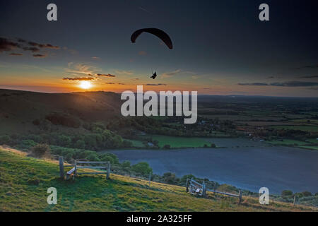 Ein Mann paraglides über den Süden Nationalpark während des Sonnenuntergangs. Großbritannien Stockfoto