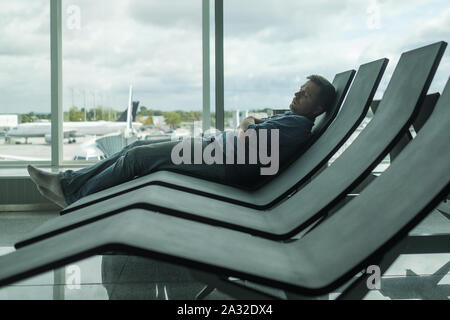 Reifer Mann im Flughafen schlafen auf einer Werkbank Stockfoto