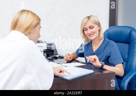 Kosmetologie Service. Junge Frau Schönheitsklinik sitzen mit Arzt Auswahl verfahren im Gespräch mit dem Arzt freudige Stockfoto