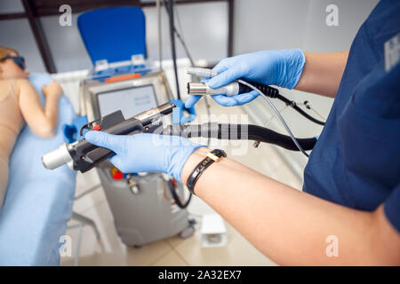 Kosmetologie Service. Junge Frau von Schönheit Klinik Arzt in Handschuhe close-up einrichten Laser zur Haarentfernung Stockfoto