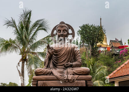 Si Racha, Thailand - 16. März 2019: Bronze Statue sitzend erleuchtet, mitleidsvollen Bodhisattvas mit Halo auf Ko Loi Insel unter Silber Himmel mit Stockfoto