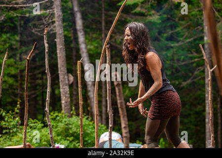 Eine inspirierende kaukasische Frau gesehen, Menschen helfen durch Bewusstsein Yoga Übungen während eines woodland Retreat, Gesang und Geschrei mit Raum für Kopieren. Stockfoto