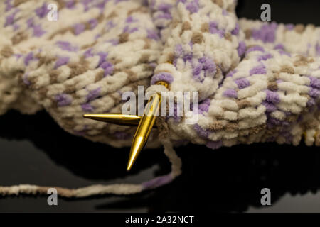 Handwerk und Handarbeit Konzept - Nahaufnahme der Stricknadeln und Kugeln aus Garnen mit unfertigen Schal Stockfoto