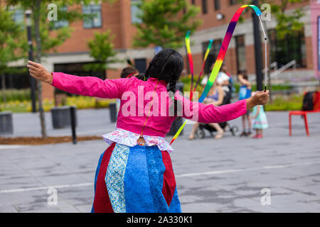 Eine Nahaufnahme und Rückansicht einer Tänzerin in leuchtenden Kleidern bekleidet, Ribbon twirling während einer Feier der einheimischen Musik und Kultur. Stockfoto