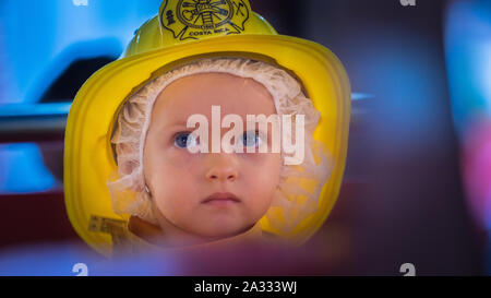 Ein schönes ukrainisches Mädchen mit blauen Augen, das einen gelben Feuerwehrhelm trägt, schaut ernsthaft in die Ferne Stockfoto