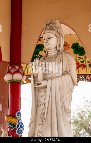 Si Racha, Thailand - März 16, 2019: Nahaufnahme von Graue Statue von Guan Yin auf ihre offene kreisrunde Heiligtum auf Ko Loi Insel. Unterstützt von Rot, Beige und Weiß Stockfoto