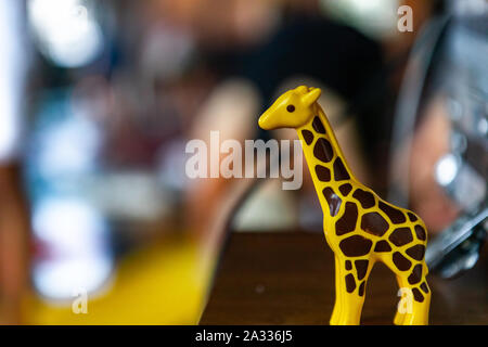 Eine Nahaufnahme und seitlichen Profil anzeigen eines süßen und bunten Kunststoff giraffe Figur stehend an der Vorderseite eines gym Session mit verschwommenen Hintergrund und Kopieren. Stockfoto
