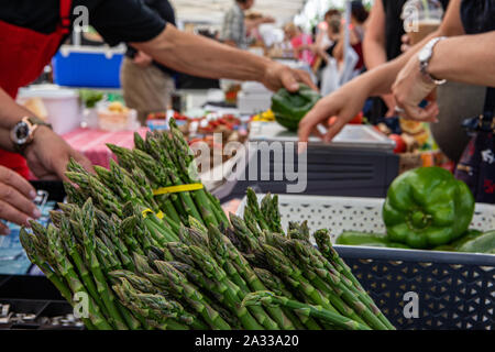Nährstoff reichen Spargel ist in Bündeln auf einem Markt gesehen, Stall, unscharfe Händlern und Kunden im Hintergrund sind mit Raum für Exemplar gesehen. Stockfoto