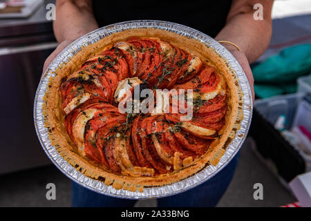 Eine Detailansicht eines Bäckers Holding eine frisch zubereitete Käse und Tomaten herzhafte Torte. Backwaren zum Verkauf an Farmer's Market Stockfoto