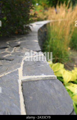 Stein geschwungenen Stützmauer im Garten Stockfoto