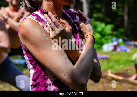 Eine Detailansicht einer jungen Frau trägt einen bunten rosa Top mit den Armen über der Brust während einer ständigen Übung der Meditation in der Natur gekreuzt. Stockfoto