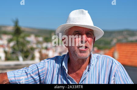 Taille bis Portrait von ein älterer Mann mit einem Hut mit stadtbild von Primosten in Kroatien im Hintergrund Stockfoto