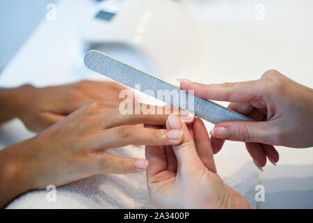 Frau in einem Nails Salon empfangen einer Maniküre mit Nagelfeile Stockfoto