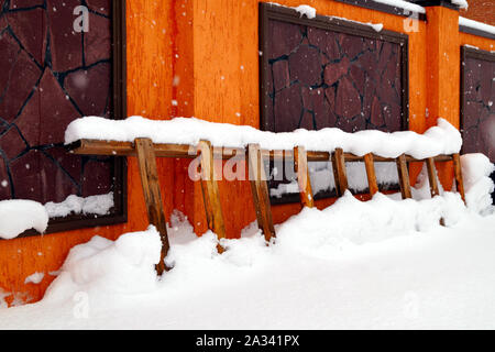 Viel Schnee liegt auf einem Wohngebäude und große Schneeverwehungen um. Jahreszeiten. Stockfoto